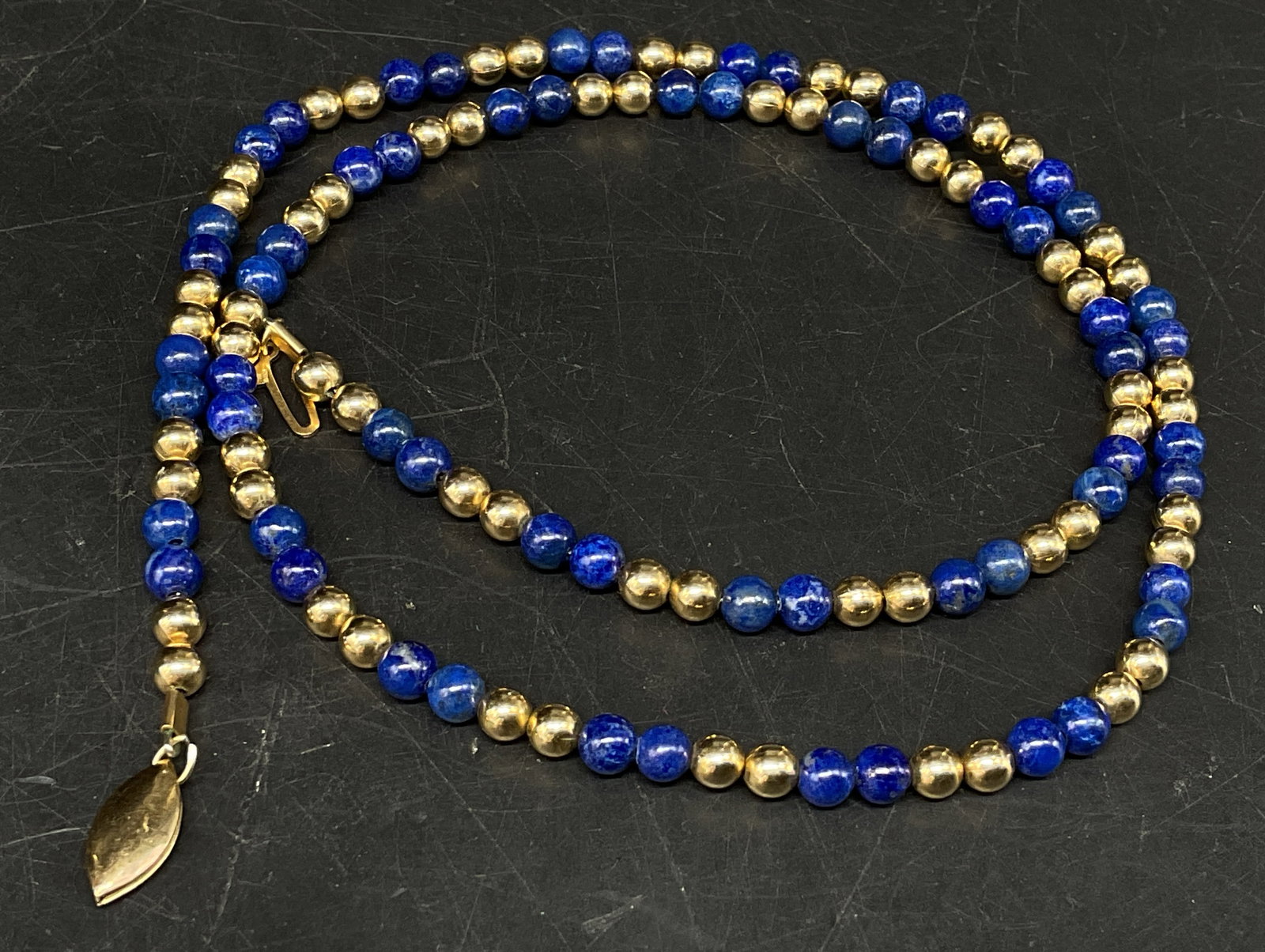 Semi-Precious Gem & Gold Filled Beaded Necklace: Beaded Necklace. Semi-Precious Blue Gemstone beads, appears to be lapis lazuli. Gold-Filled beads. Clasp marked 1/20 14K. Some twisting. Measures app 19in L. necklaces, beads, semi-precious gemstones,