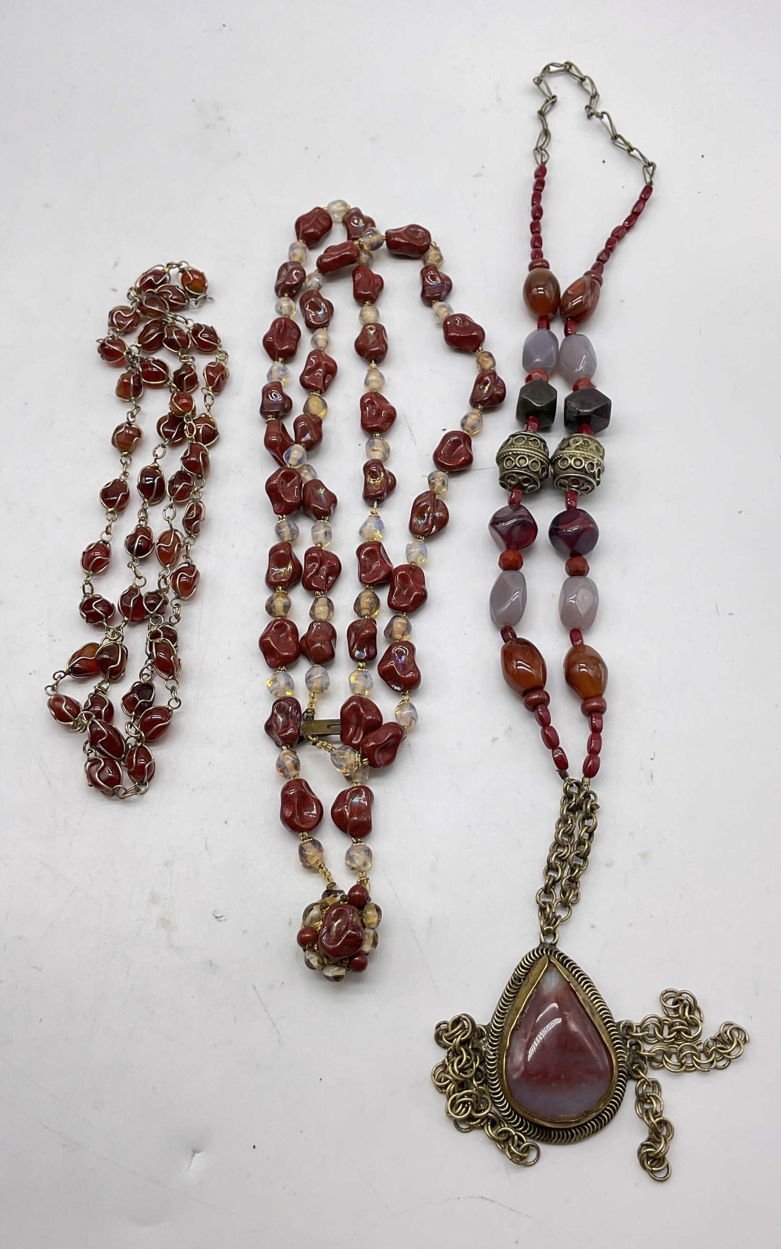 Lot 3 Vtg Assorted Beaded & Semiprecious Necklaces: Lot of 3 vintage assorted beaded and semiprecious necklaces. Red and clear polished stone and glass beads necklace with cluster pendant. Red semiprecious gemstone necklace with overlay. Multicolored s