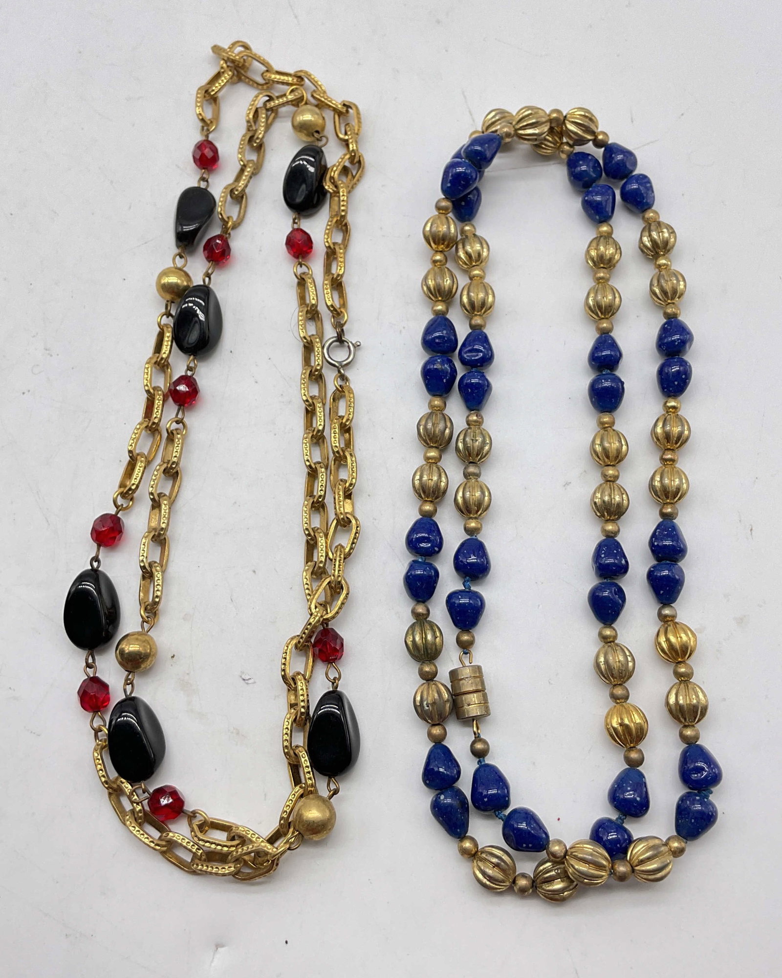 Lot 2 Vintage Assorted Beaded Necklaces: Lot of 2 vintage assorted beaded necklaces. Blue glass beads and ribbed gold toned beads with gold toned spacers. Black polished stones and red glass beads with gold toned beads and chain link.
