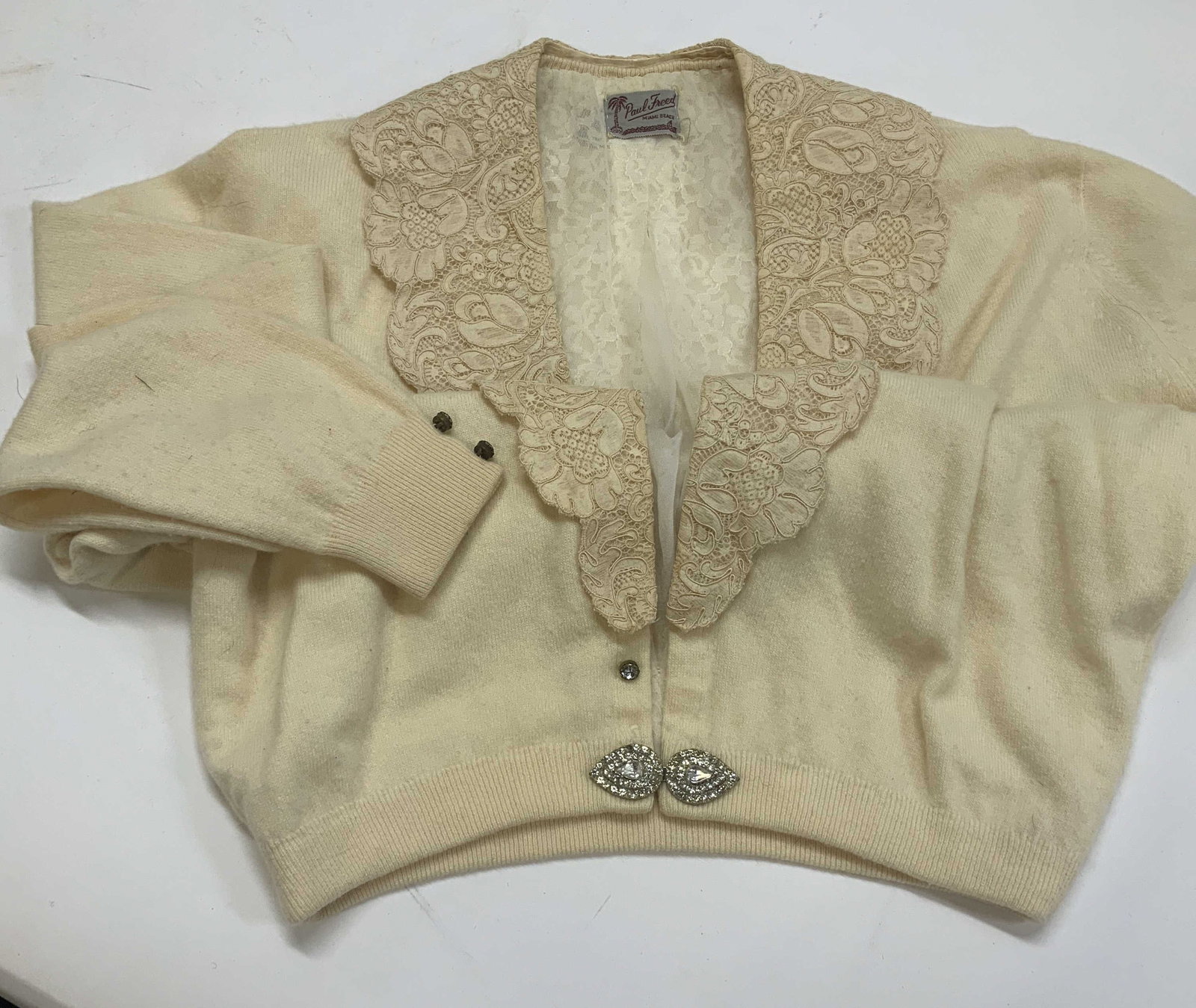 Vntg PAUL FREED MIAMI BEACH lace sweater: Vntg PAUL FREED MIAMI BEACH lace sweater. The sweater features a wide detachable lace collar. It is double lined with a layer of lace and a layer of sheer on top. It has a rhinestone sweater clip and 