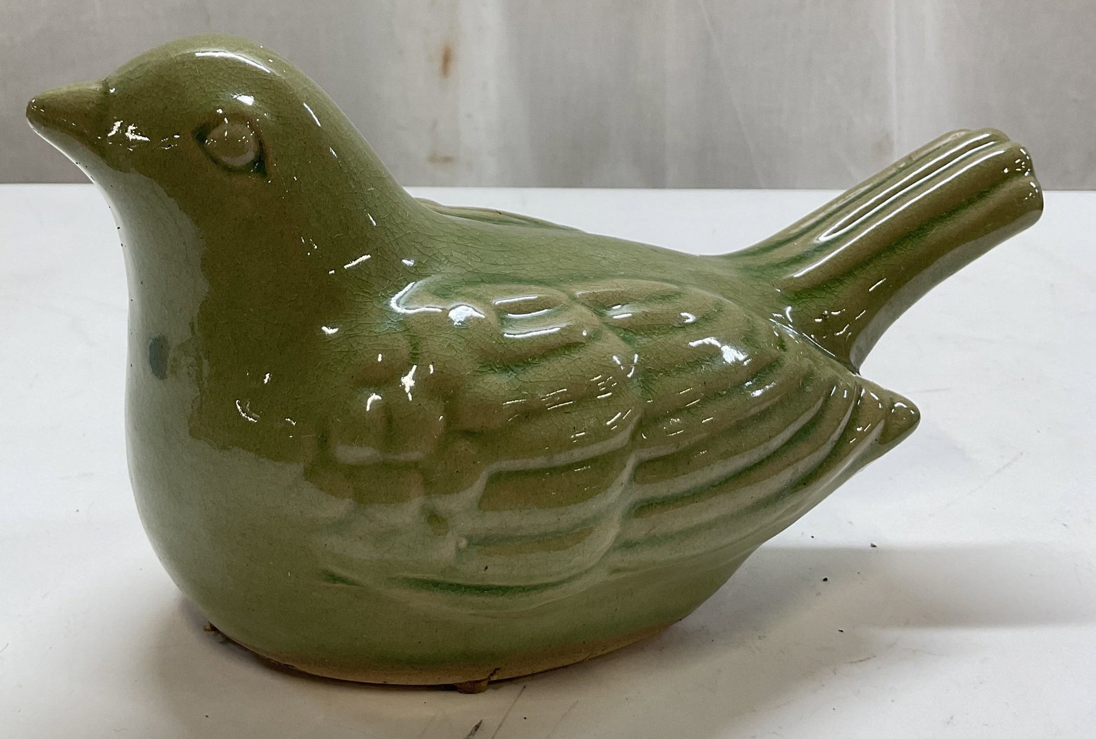 Vintage Green Glazed Ceramic Bird Figure: Vintage green glazed ceramic bird figure. Bird figure with detailed features, ribbed surface. Green glazed, glossy finish. Measures approx 6 x 10 x 5 inches. Crazing and scratching. Figure, ceramic