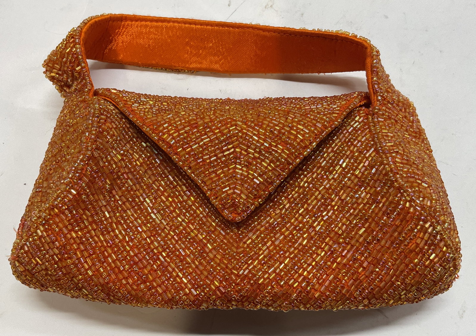 K.C. Malhan Orange Beaded Small Purse India: K.C. Malhan orange beaded small purse. Made in India. 100% viscose. Orange beaded design. Attached handle. Flap with magnetic button closure. Interior compartments. Measures approx 4.5 x 8 inches.