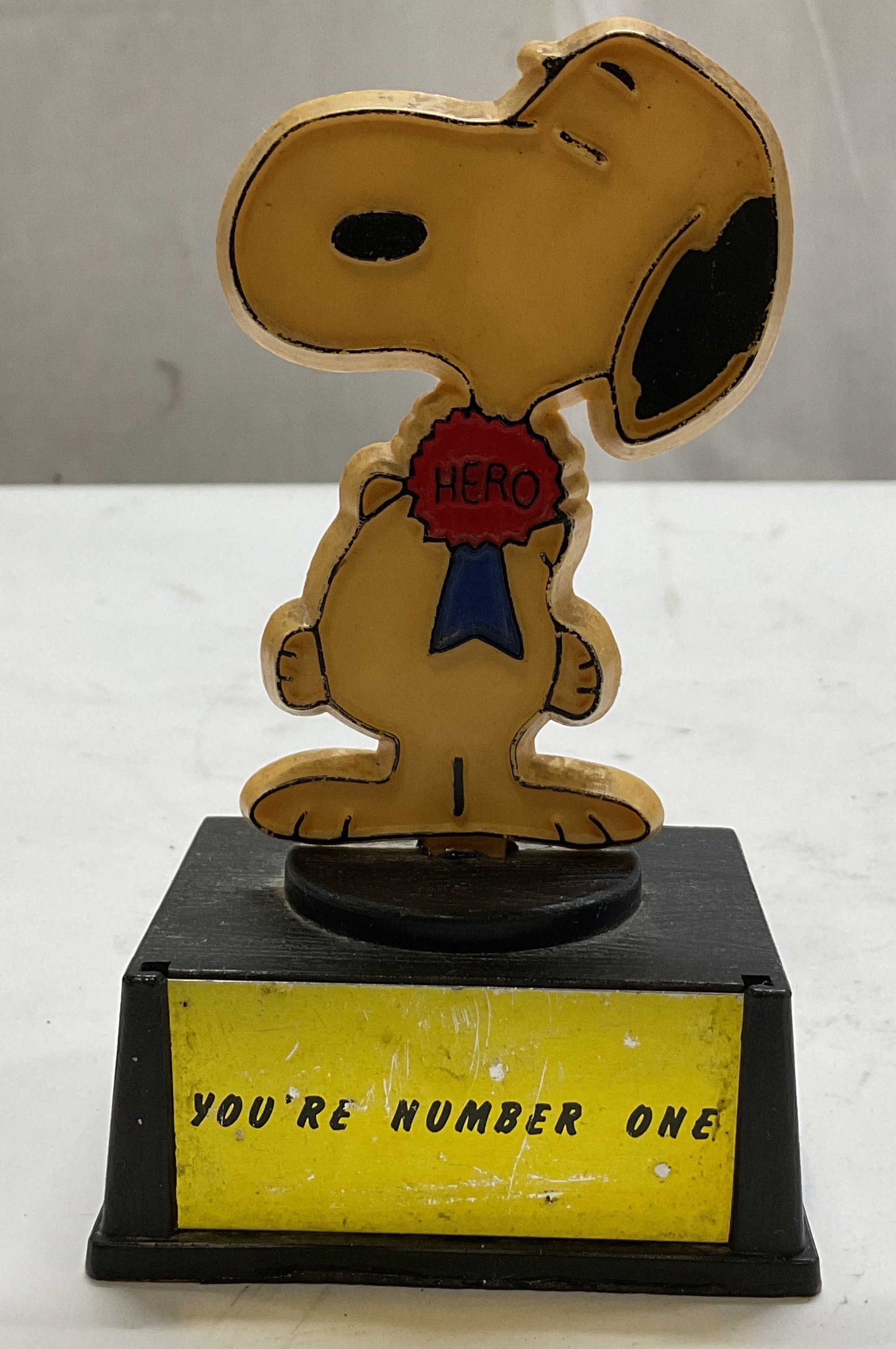 1958 Aviva Snoopy Number 1 Hero Trophy Hong Kong: 1958 Aviva Snoopy Number 1 Hero trophy. Hand crafted in Hong Kong. Copyright 1958 United Feature Syndicate Inc. Made by Aviva. Snoopy wears a blue ribbon with a red Hero badge. Black pedestal base