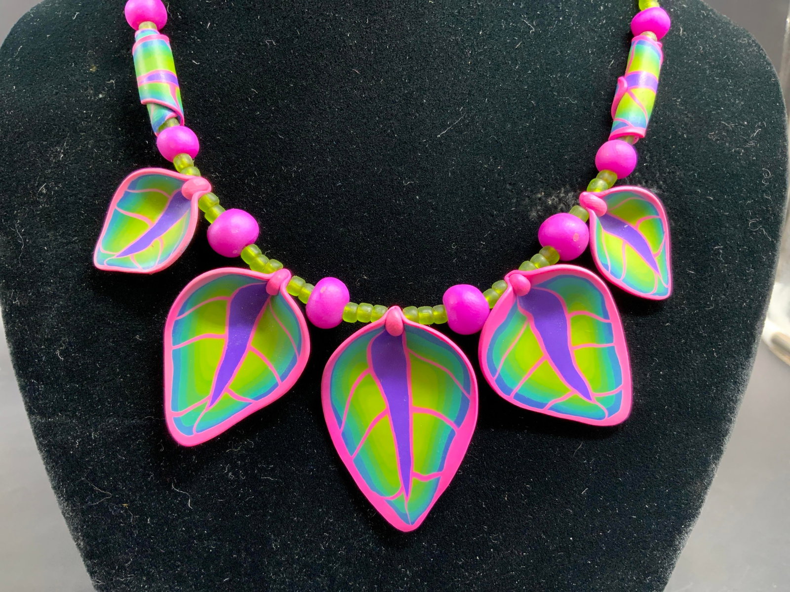 Handmade Colorful leaf Pendant Necklace: Artisan crafted handmade statement necklace made possibly from polymer clay decorated with multi colored leaf pendants and mixed beads, wearable art created using complex millefiori cane technique in