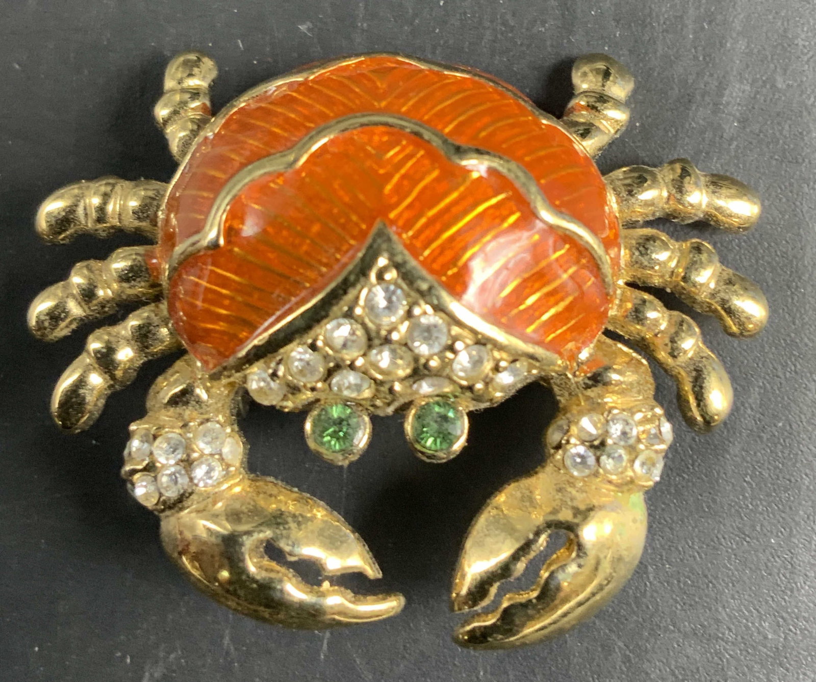 Gold tone orange Crab Brooch: Vintage Gold toned jewelry crab brooch featuring an orange enamel shell, green rhinestone eyes, and clear crystal rhinestone accents along the top and claws, measures app 1.5 inches -j