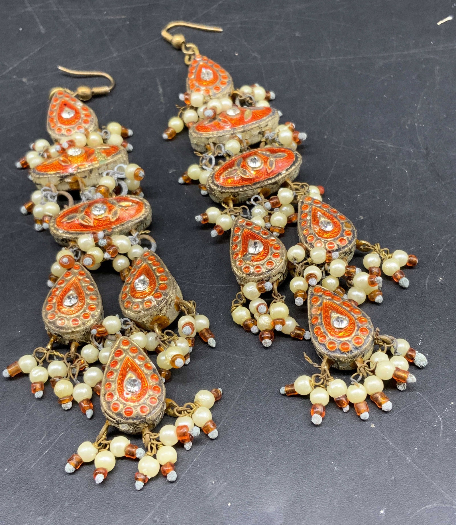 Dangling Long orange Traditional Indian Earrings: Long dangling vibrant orange traditional Indian dangling earrings, intricately decorated with enamel Meenakari work, Kundan settings and small faux pearl clusters, each measures length app 4.25