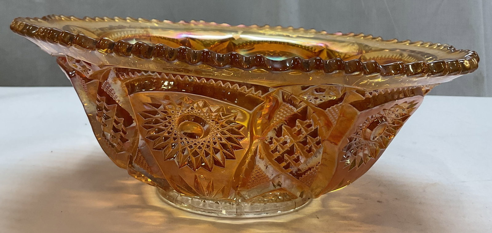 Vintage Marigold Carnival Glass Bowl: Vintage marigold carnival glass bowl. Scalloped sawtooth rim. Cut hobstar and sunburst patterns. Orange marigold iridescent. Measures ht approx 4.5 inches diam approx 11 inches. Scratching. Bowl,