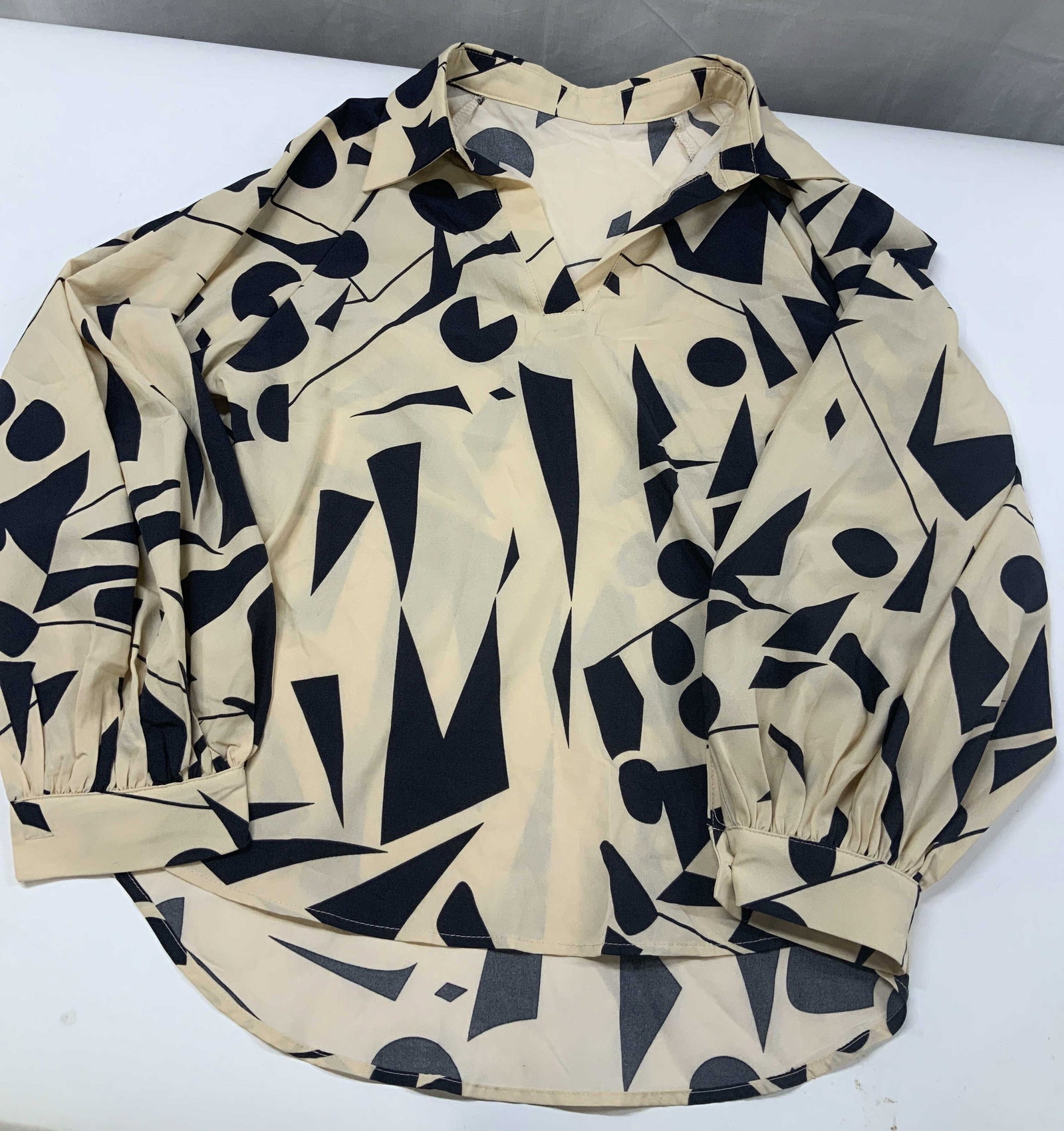 Abstract geometric print blouse: Abstract geometric print blouse. Shirt features a cream background with a navy blue print. Made of 100% polyester in size medium. I sharp v neckline integrated with flat laying Johnny collar. Full len