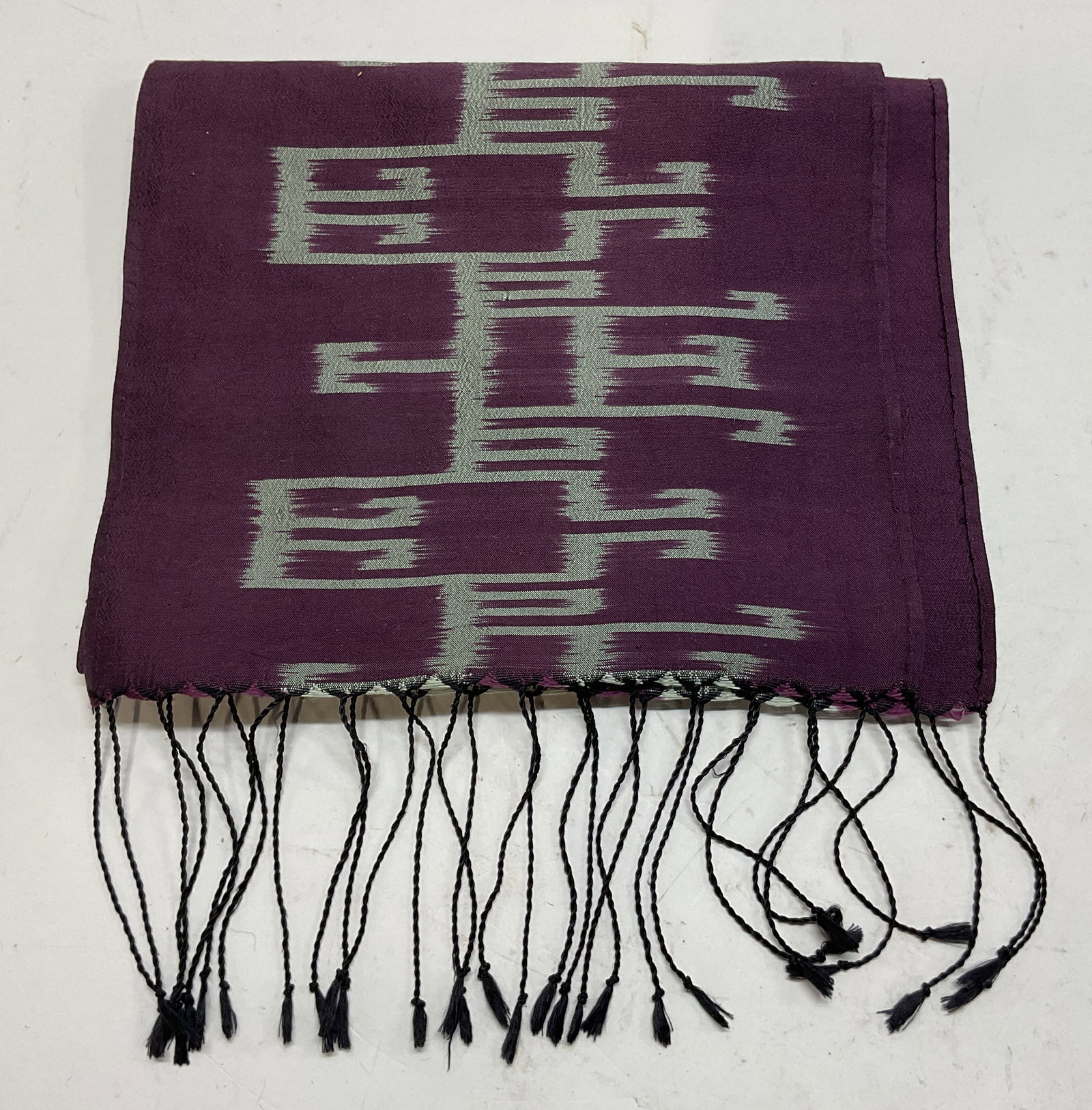 Carol Cassidy Lao Textiles Purple Silk Scarf: Lao Textiles by Carol Cassidy scarf. Hand woven silk material. Black fringed trim. Purple and grey abstract geometric pattern. Measures approx 10 x 62 inches. Wear consistent with exposure. Scarf, sil