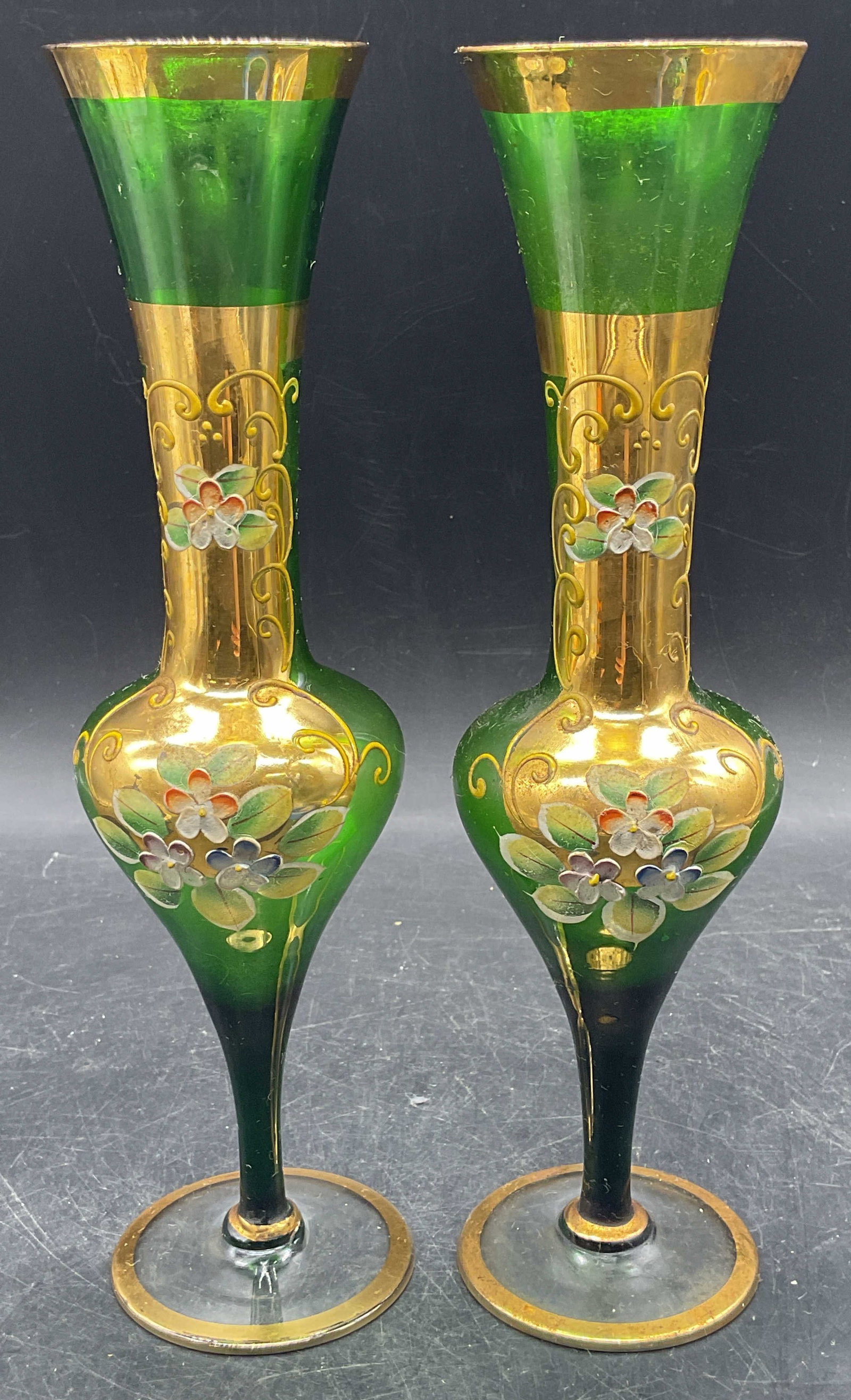 Pair Bohemian Green Gilt Art Glass Vases: Pair of vintage Bohemian style green and clear art glass vases. Hand painted and gilt decoration with floral motif. Fluted bulb bowls with tapered stems and round footed bases. Measures approx. 2.5 x