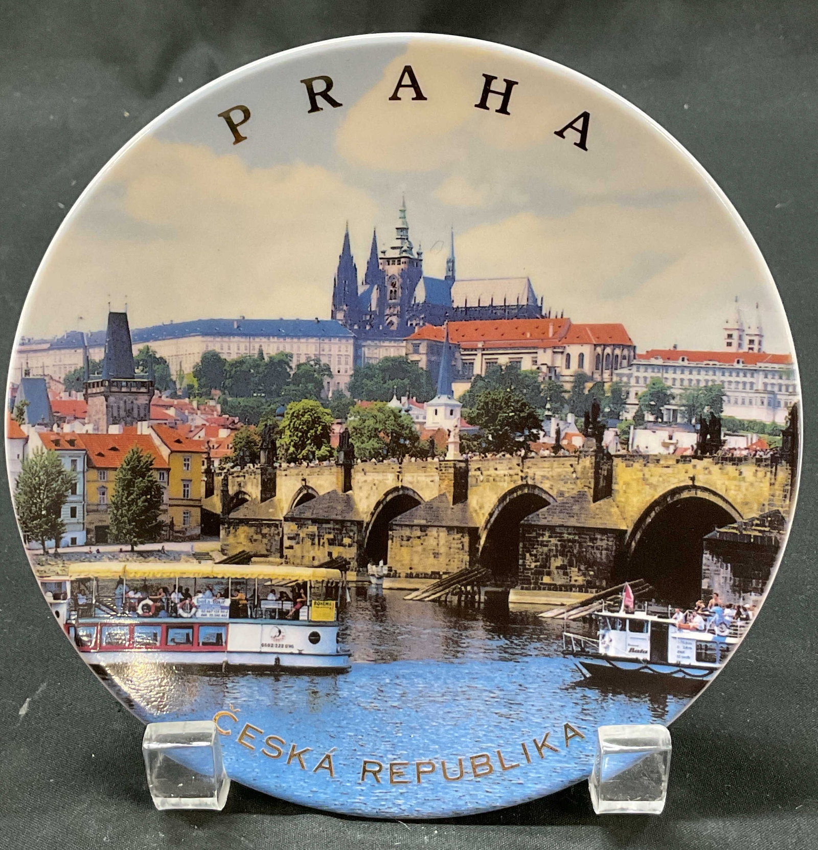 Praha Ceska Republika Souvenir Wall Plate: Praha Ceska Republika porcelain decorative souvenir wall plate. Round plate. Surface reads Praha Ceska Republika in gilt lettering. Features a scenic view of Prague including the Vltava River, Charles