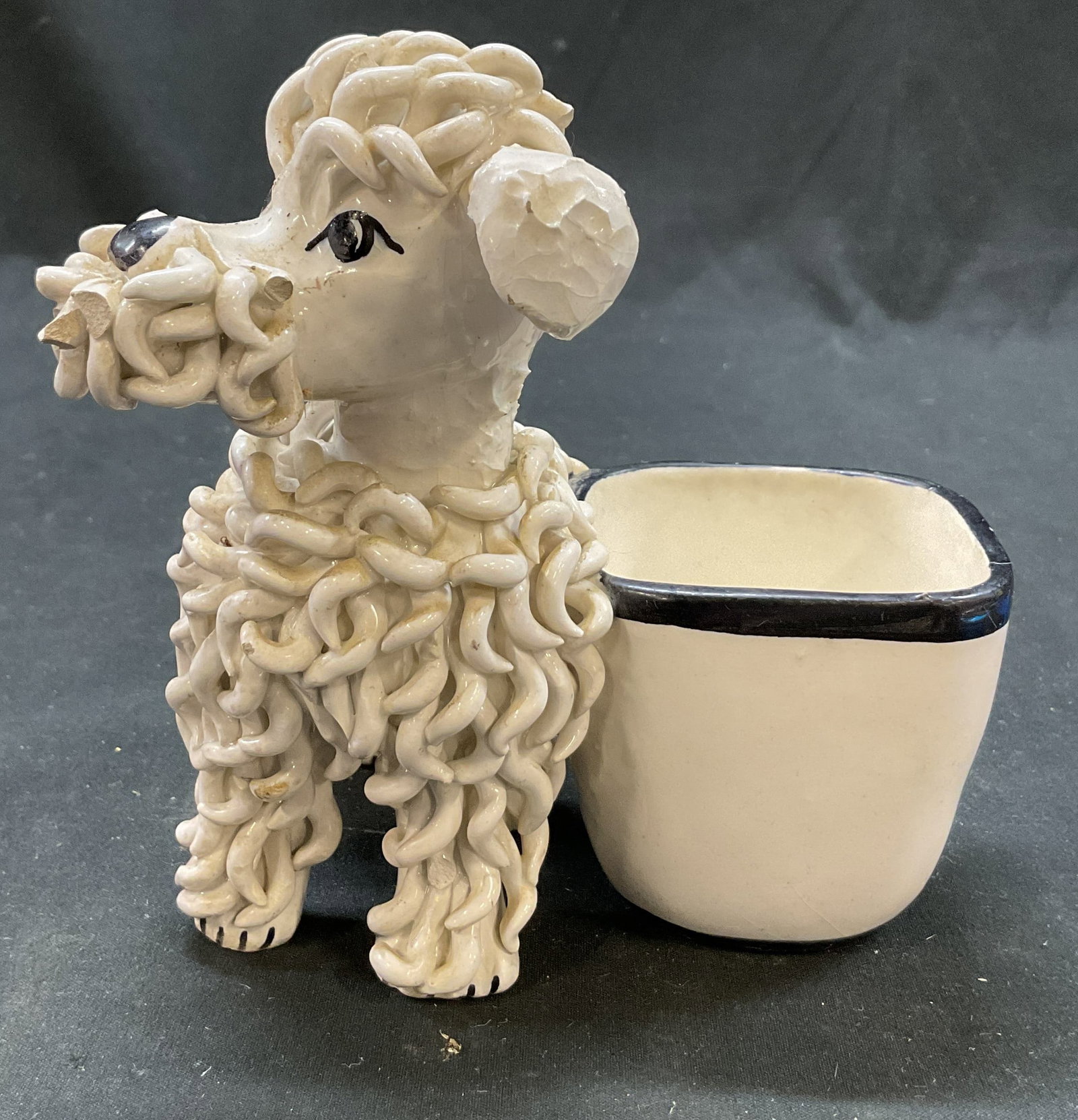 Vintage White Ceramic Poodle Planter Italy: Vintage white ceramic poodle planter. Marked made in Italy on underside. White cup with painted black rim. Intricate spaghetti curls design. Painted features in black. Glossy finish. Measures approx 4