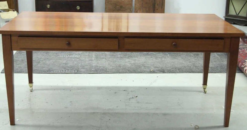 Contemporary Modern Cherry Executive Desk: Tapered legs. Two drawers. Front legs with brass caster wheels. Height 30 inches. Length 71 inches. Depth 36 inches.
