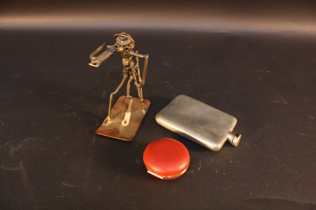 Group lot Gentleman's Table articles: Group lot of table articles included Pewter Flask marked made in England signed and hallmarked with trumpet, found objects metal sculpture of man in a cast, red leather encased clock marked Bradley. P