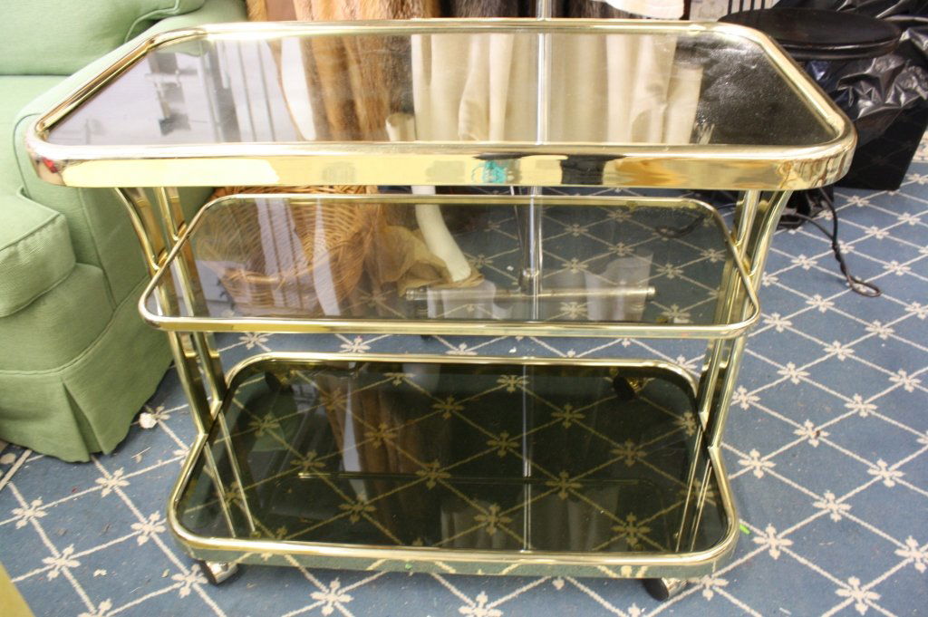 Mid century modern Bar Cart: Vintage mid century modern and contemporary in feel bar cart trolley or tea cart. Tube like Brass frame with three smoked glass mirror top and smoked glass two under shelves. On wheels and handled. Me