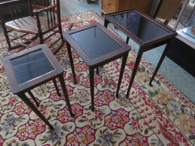 Three Mahogany Nesting Side Tables: Mahogany with black glass inserts. Middle table glass cracked. Largest side table measures 24 in. H x 20 in. W x 14 in. D From a Pelham Manor, NY Estate