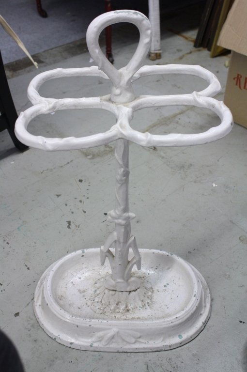 White Painted Metal Umbrella Stand: Floral design on bottom, four holders for umbrellas, measures 27 inches high by 10 inches wide by 13 inches deep