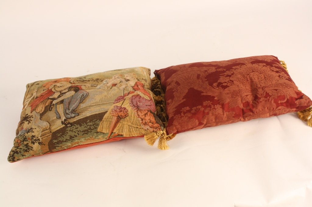 Two throw pillows silk and tapestry: One throw pillow maroon sik damask with gold trim and gold tassels, one throw pillow Tapestry of Victorian scene and textured woven silk.Largest measures 17 inches by ten inches. Decor