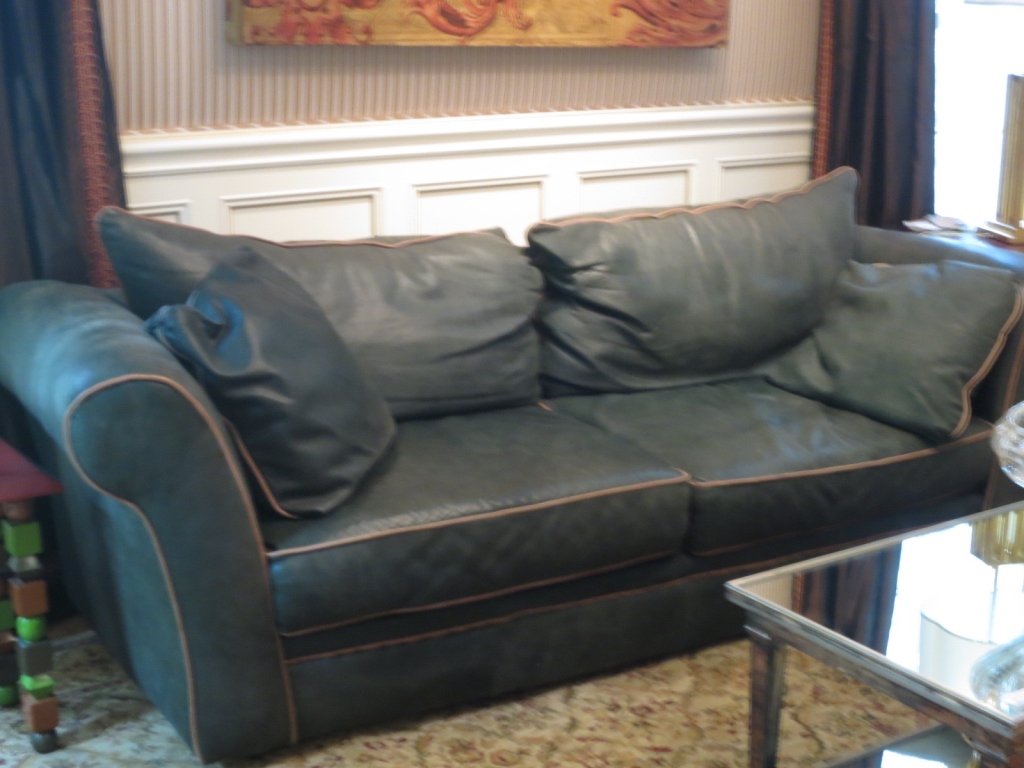 Green Leather Sofa with piping: Green leather Sofa with beige leather piping trim. Measures seven feet length and three feet depth. Loos back cushions, Loose side Cushions and loose seat cushions. Decor