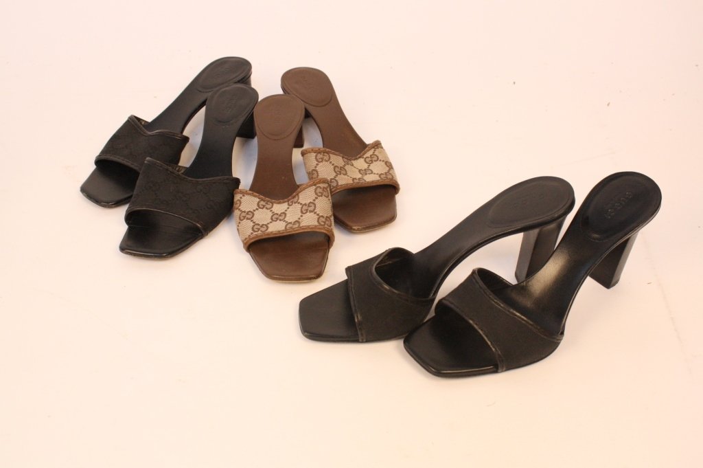 Three Pair GUCCI Slides Size 9B: Two pair medium heel height measuring 1-1/2 inches with signature pattern. One pair Brown on Tan. One pair Black on Black with soles lightly worn. Also, one black on black pair with higher heel slight