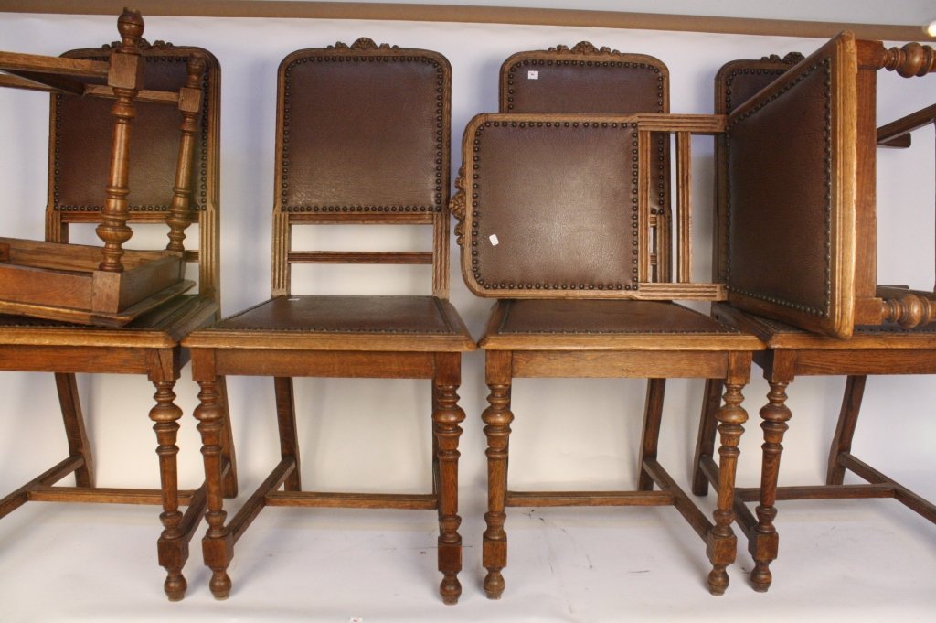 Six Vintage Oak Chairs with Brown Leather Inserts: Hand forged nail heads and crackle design leather. Carved wood bow tie top and articulated legs. Very good condition, one chair has one crack in join that needs repair.
