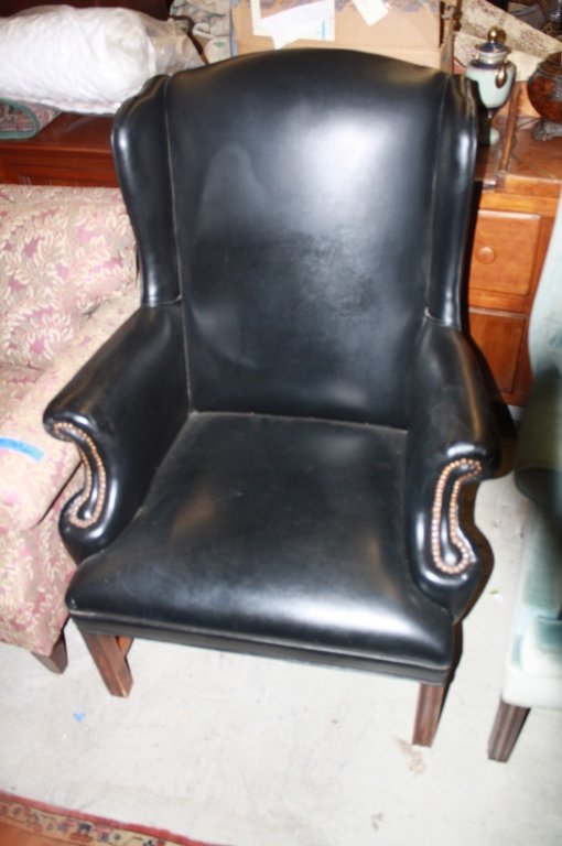 Vintage Black leather wing chair: Vintage black Leather wing chair, armchair with studded accents and wood base, small corner tear in leather. , measuring in inches 42H X 32W X 32D.