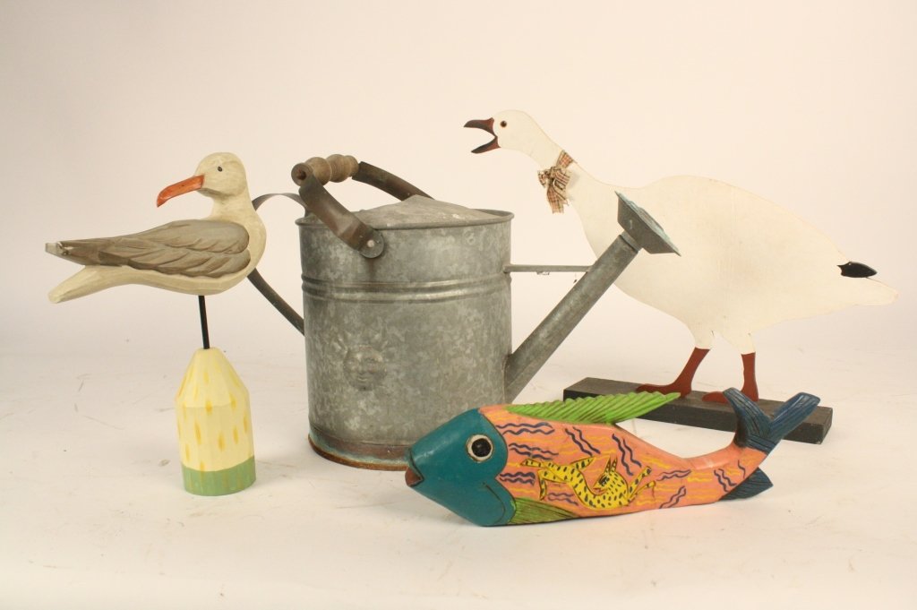 Folk Art Watering Can Group: Group includes antique metal and wood watering can with sun emblem, measures 15 inches tall by 19 inches wide, carved wood duck, painted white, measures 14 inches wide, carved wood fish and carved woo
