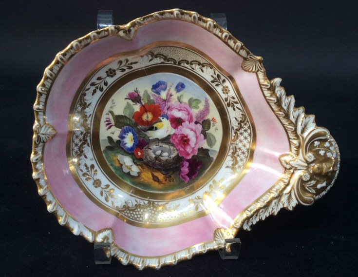 Antique Porcelain Shaped Dish C 1820: a very colorful antique 19th century shaped dish. In the center of this piece there are pink orange blue lavender flowers accompany a bird guarding its nest of eggs. It has a shaped gilt scalloped bor