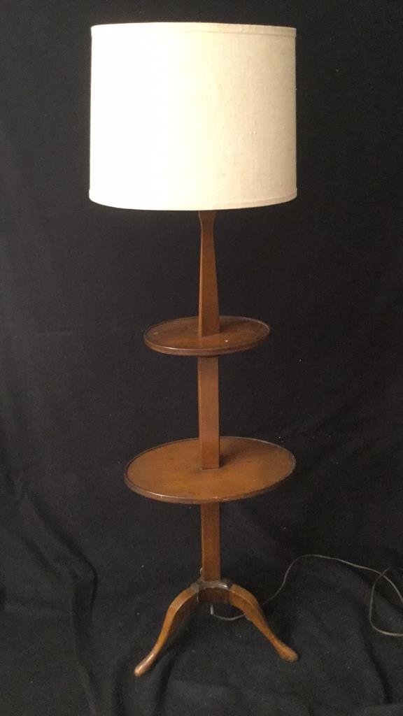 Wooden Floor Lamp with Shelves: Floor lamp on 3 legs with 2 surfaces. Vintage style. Wood with burlap shade. Measures 60 inches tall by 17 inches wide by 13 inches deep. Used condition. Feels worn.