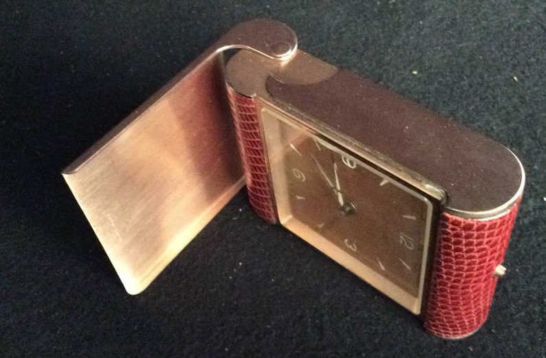 CYMA Leather and Brass Desk Travel Clock: Vintage Clock with original. Box and papers marked. For CYMA , instruction booklet. Case rose Gold textured brass plated, crocks file skin casing, hinged case opening to face. Measures app 3.5 length 