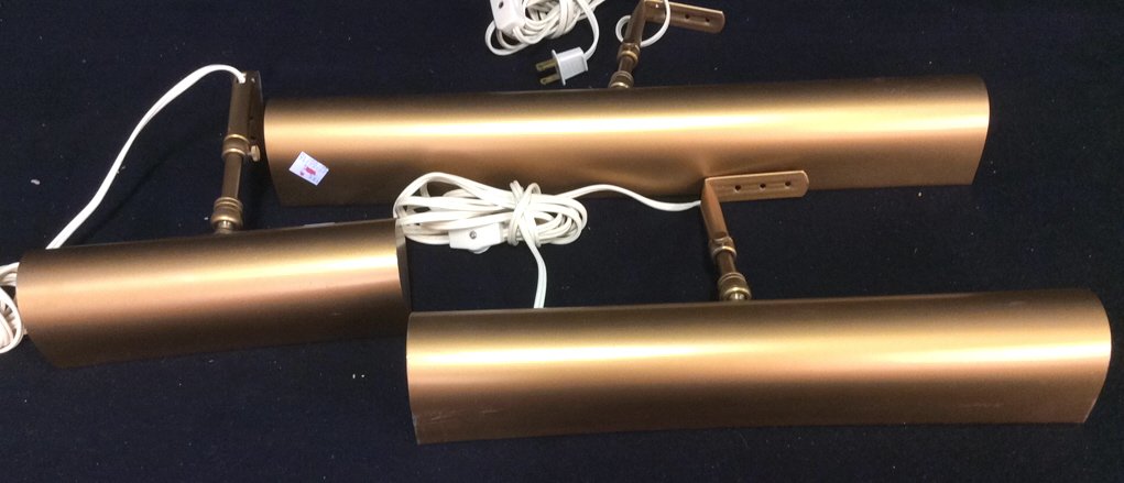3 Brushed Gold Toned Picture Lights: Task lighting, over artwork lighting, piano lighting, brushed gold toned wall mounted horizontal lights. Longest measures 18 inches. Labels in each for House of Troy, Hyde Park Vermont