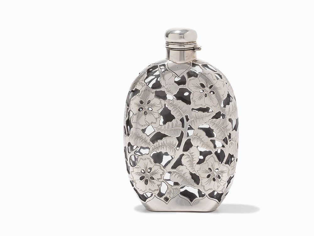 Silver Overlay Glass Flask, UK, c. 1900: Engraved silver-plate overlay and glass and cork UK, circa 1900 Worn away maker mark with patent number along the base Twist and flip lid Overlay with floral engraved motifs Dimensions (length x width