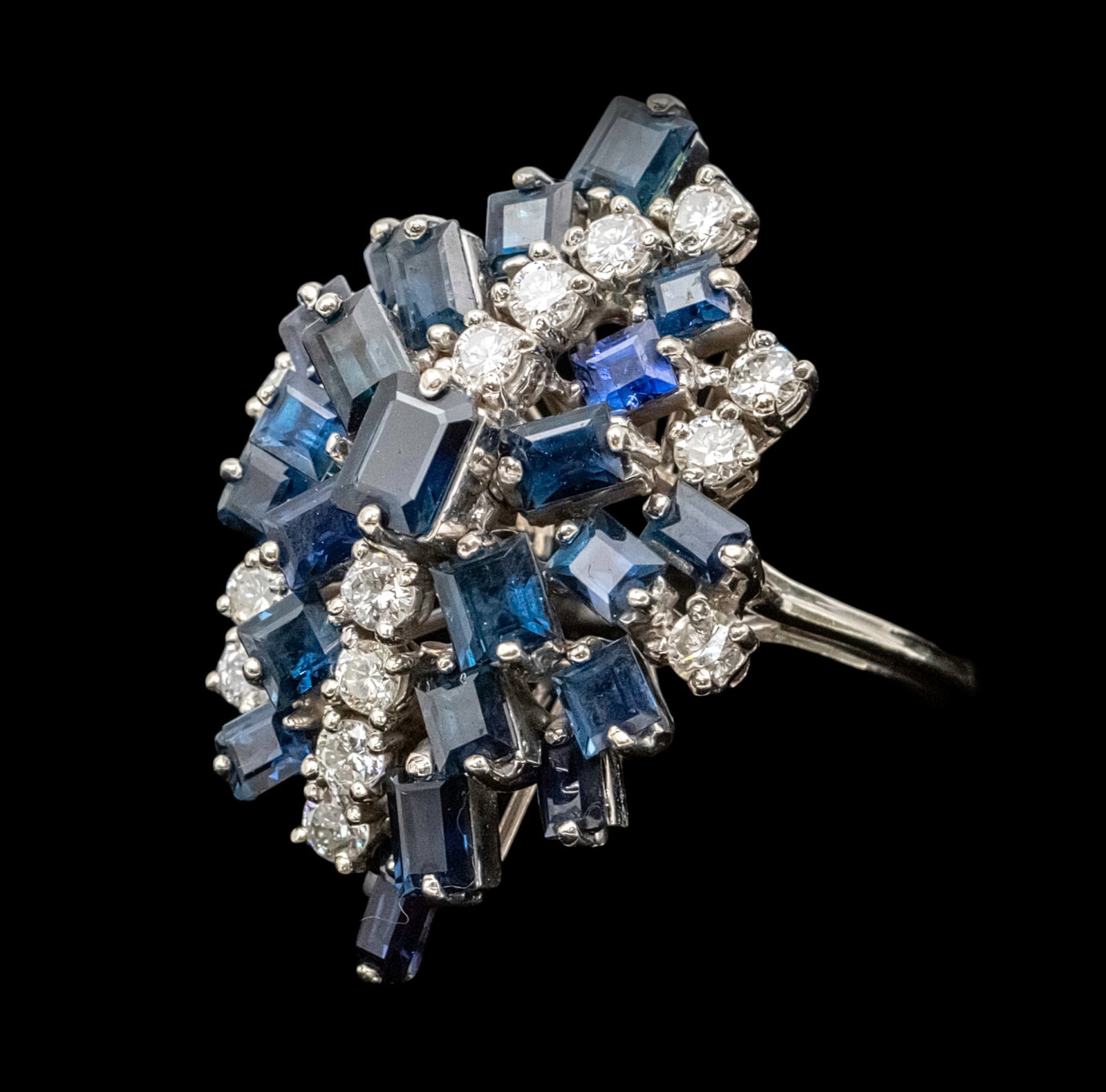 14k White Gold Diamond and Sapphire Ring.: 14k White Gold Diamond and Sapphire Ring. 14 diamonds in total weight of about 1.10ct. 23 sapphires in different cuts and sizes. Marked. Top of the ring: 34mm. Size: 7.75. 12.23gr.
