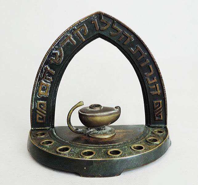 Pal-Bell Heavy Cast Brass Hanukkah Menorah Judaica: Israel, 1950s. The arched back with the Hebrew phrase - Hanerut Halalu Kosdesh Hem (these candles are sacred). Fronted by 8 candleholders and a standalone (portable) servant light (Shamosh). Marked - 