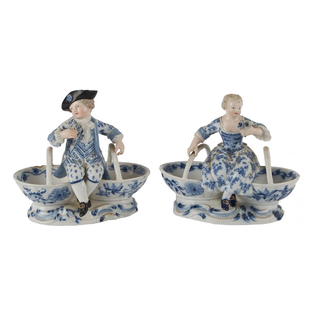 COPPIA SALIERINE in porcellana di Meissen raffiguranti: COPPIA SALIERINE in porcellana di Meissen raffiguranti "Bambini con panieri" (difetti). Germania XIX secolo Misure: cm 13,5 x 8 h cm 13