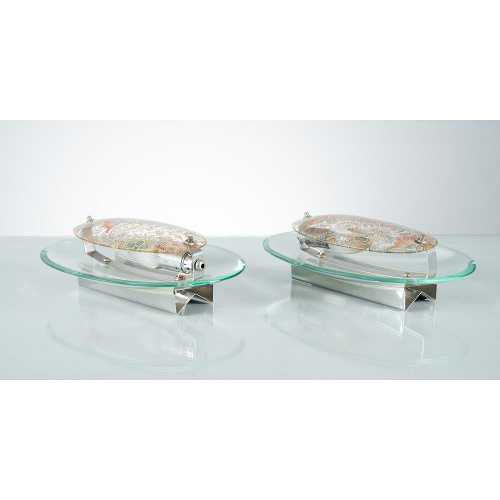 VECA (Attr.le), Coppia di lampade da parete: VECA (Attr.le) Produzione Italia 1970 ca. Coppia di lampade da parete ad una luce, struttura in metallo cromato, diffusori in cristallo ovale trasparente e decorato a motivi floreali arancione. Giunti