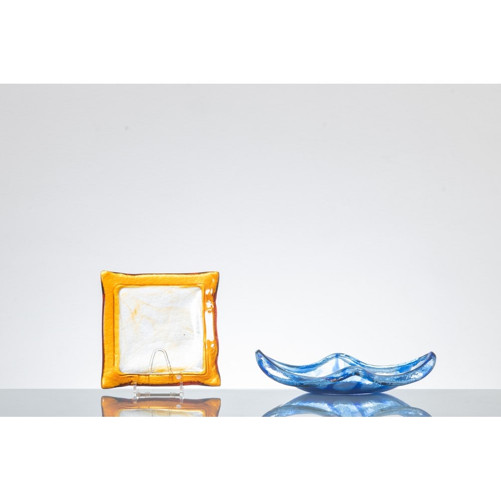 LA MURRINA, Due svuotatasche: LA MURRINA Produzione Murano, Italia 1980 ca. Due svuotatasche in vetro uno neo toni ambra ed incolore, uno neo toni blu, corpo quadrata lievemente concavo. Marchio di produzione. Cm 19 x 19 Alt. 3 -