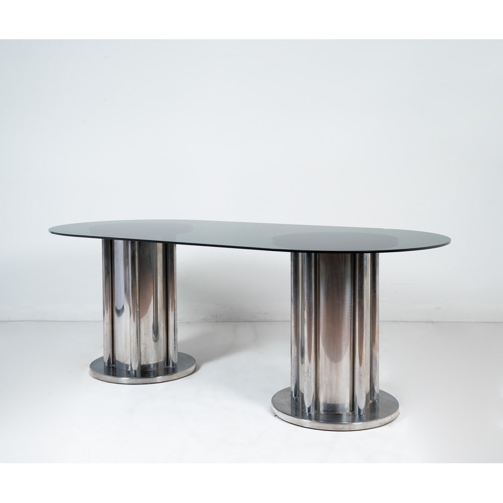 ANTONIA ASTORI (Attr.le), Tavolo da pranzo: ANTONIA ASTORI (Attr.le) Produzione Italia 1970 ca. Tavolo da pranzo con due sostegni cilindrici a base circolare in metallo cromato, piano ovale in vetro trasparente fumè. Segni di uso. Cm 210 x