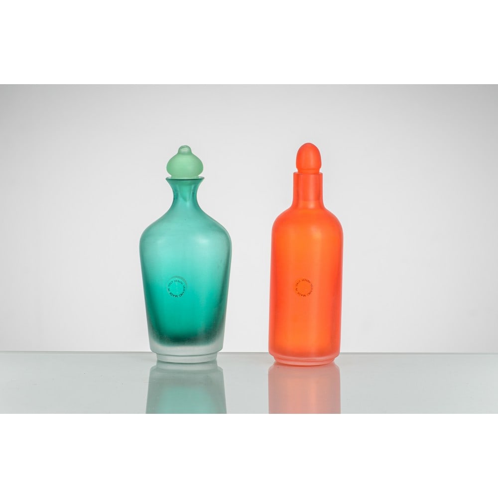 PAOLO VENINI, Due bottiglie con tappo della serie “Incisi”: PAOLO VENINI Produzione Venini, Italia 1993 ca. Due bottiglie con tappo della serie “Incisi” in vetro verde ed arancione, caratterizzate da incisioni orizzontali su tutta la superficie. Fi