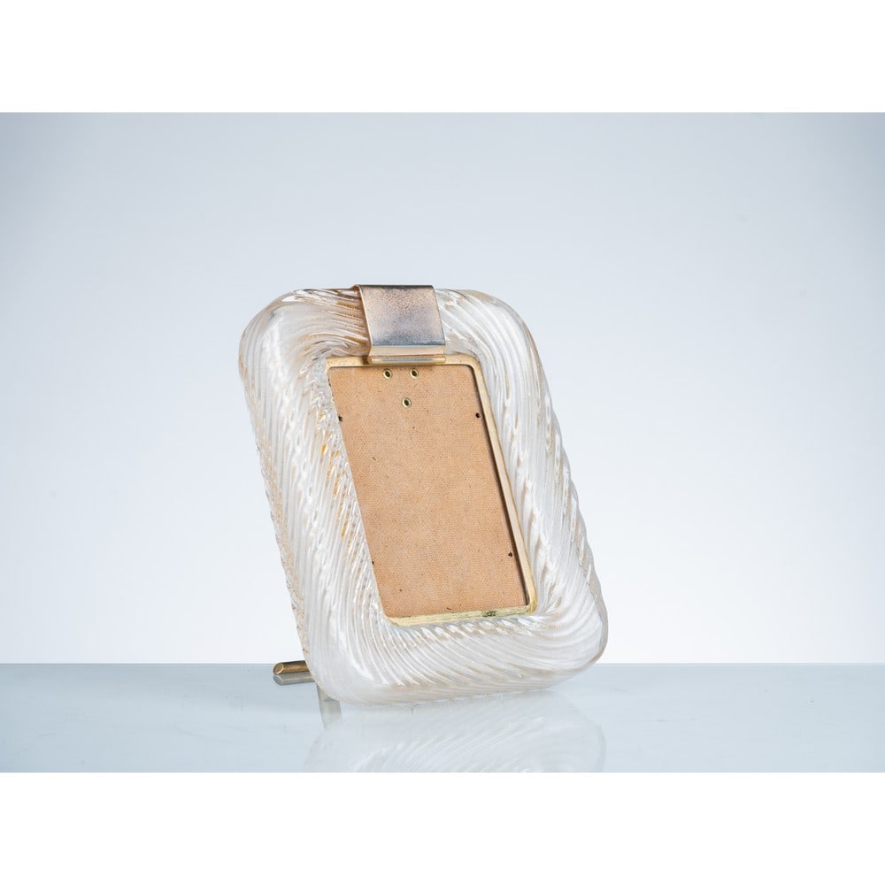 VENINI (Attr.le), Cornice portafoto in vetro: VENINI (Attr.le) Produzione Murano, Italia 1940 ca. Cornice portafoto in vetro a torciglione trasparente con montatura e decoro centrale in ottone. cm 27 x 22. Bibliografia: Catalogo altra casa d̵