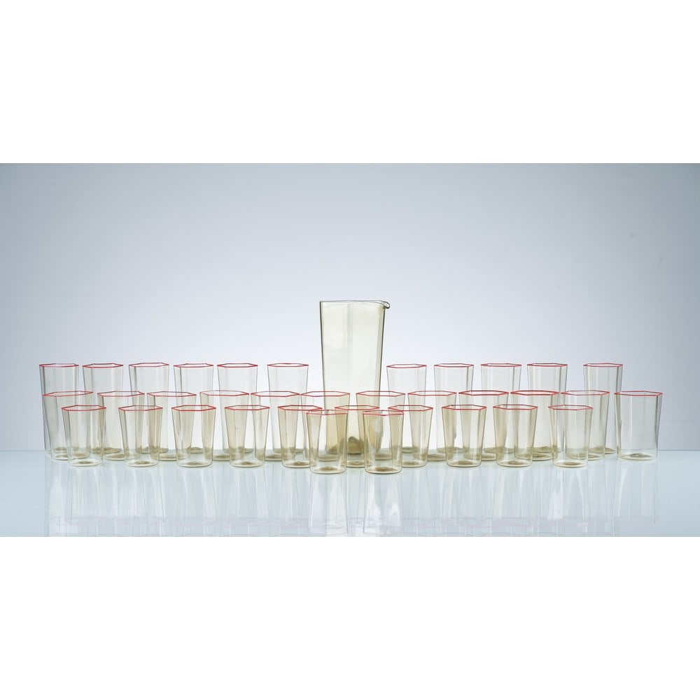 CARLO SCARPA, Caraffa e trentacinque bicchieri “Esagonale”: CARLO SCARPA Produzione Venini, Italia 1970 ca. Una caraffa e trentacinque bicchieri modello “Esagonale” in vetro soffiato pagliesco con profilo superiore rosso applicato a caldo. Undici b