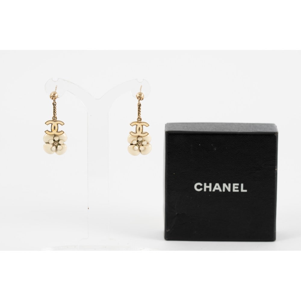 CHANEL, Orecchini pendenti con montatura in metallo: CHANEL Produzione Francia 2005 ca. Orecchini pendenti con montatura in metallo argentato, camelia e logo ”CC” in smalto avorio, chiusura a vite. Marchio di produzione e scatola originale.