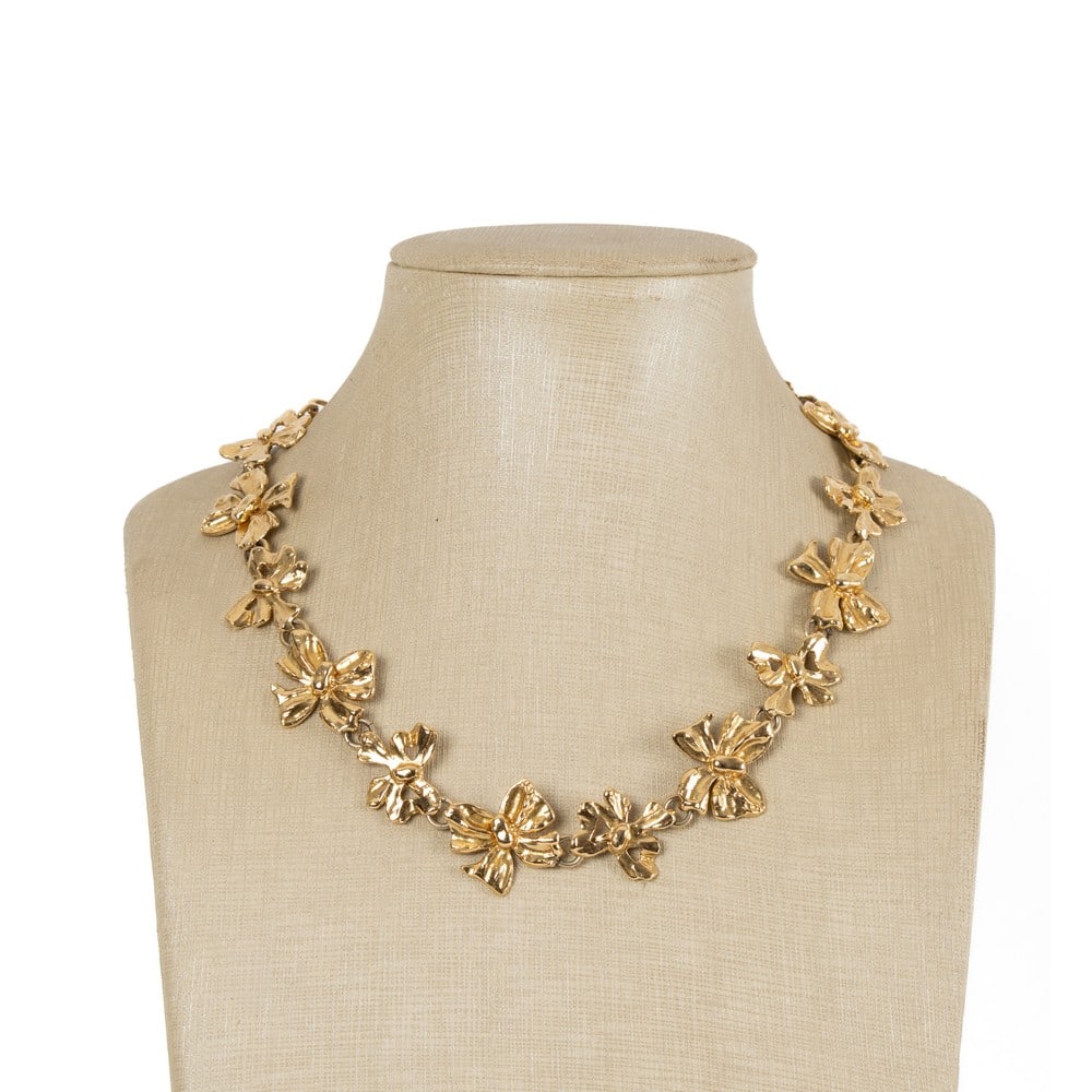 YVES SAINT LAURENT, Collana con montatura in metallo: YVES SAINT LAURENT Produzione Francia 1990 ca.Collana con montatura in metallo dorato, fiocchi di due grandezze concatenati, chiusura con gancio ad S. Marchio di produzione.