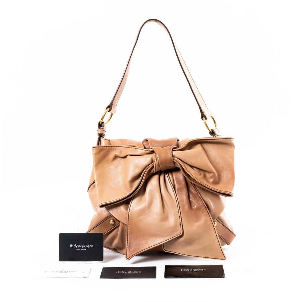 YVES SAINT LAUTENT, Borsa a tracolla: YVES SAINT LAUTENT Produzione Francia 2000 ca. Borsa a tracolla con fiocco in pelle di vitello beige, chiusura sulla patta, manico piatto, tasche interne, minuterie in metallo dorato. Card. Marchio di