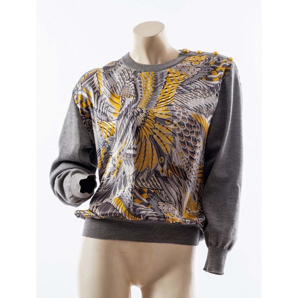 SALVATORE FERRAGAMO, Maglia in lana grigia: SALVATORE FERRAGAMO Produzione Italia 1990 ca. Maglia in lana grigia con frontale in pura seta a decori di piumaggio nei toni del grigio e giallo, scollatura a girocollo con abbottonatura laterale, bo