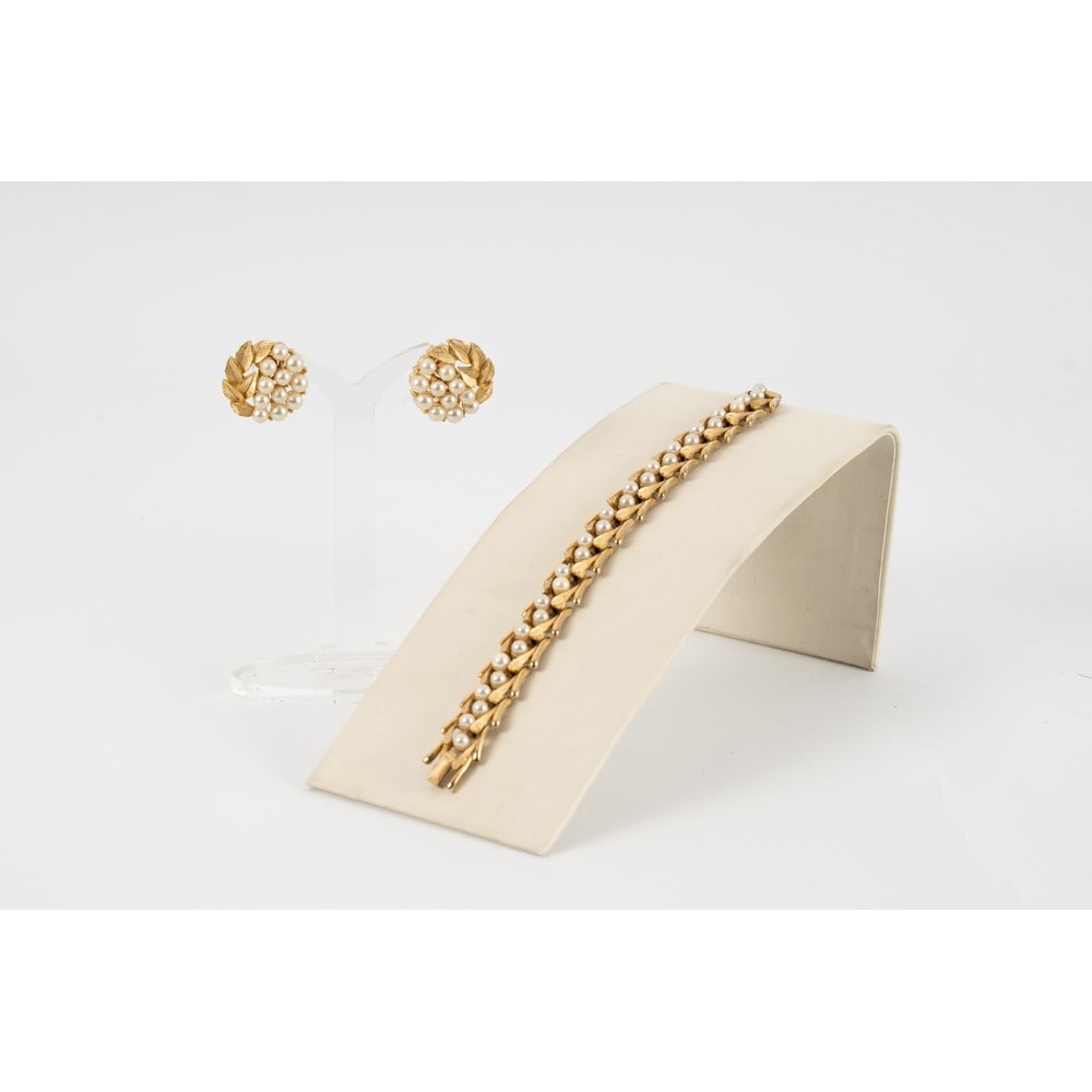 TRIFARI, Parure composta da due pezzi: TRIFARI Produzione U.S.A. 1960 ca.Parure composta da due pezzi; un bracciale semi rigido con montatura in metallo dorato, foglie stilizzate, perle , chiusura a fermaglio . Marchio di produzione. Orecc