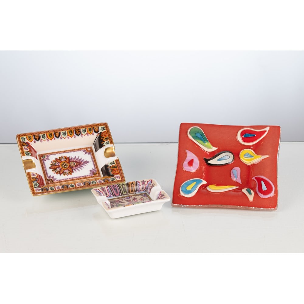 ETRO, Tre posacenere: ETRO Produzione Italia 2000 ca. Tre posacenere, due di grandezza differente in porcellana con decori paisley policromi; uno in vetro rosso con decori paisley stilizzati e policromi. Marchio di