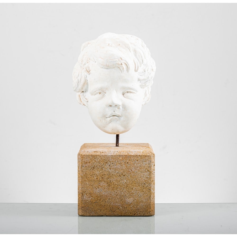 MANIFATTURA ITALIANA DEL XX SECOLO, Testa di putto: MANIFATTURA ITALIANA DEL XX SECOLO Testa di putto in pietra arenaria rivestita in gesso, base in pietra non coeva. cm Alt. 26, Alt. 48 (con base).