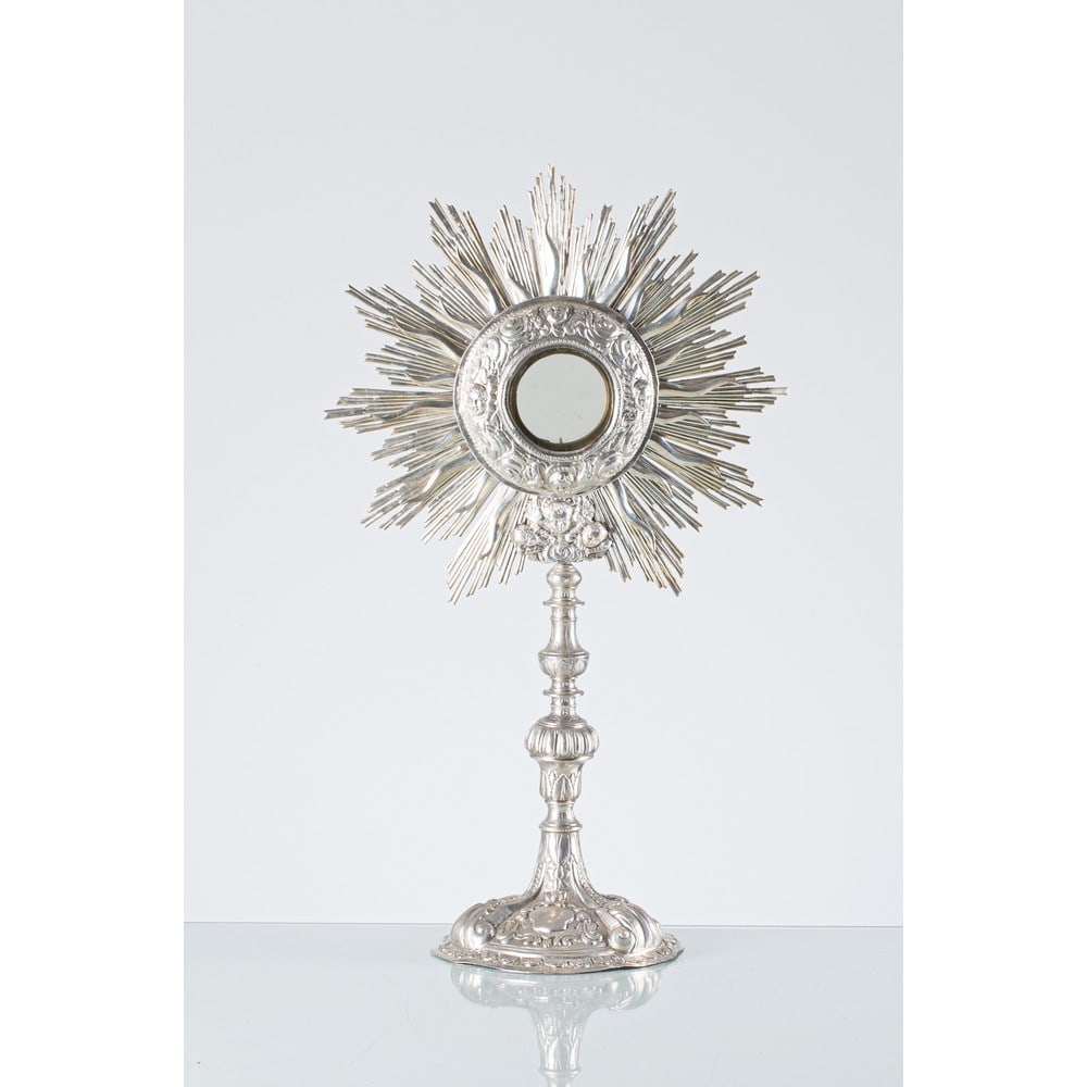 OFFICINE PALERMITANE DEL XVIII SECOLO, Ostensorio: OFFICINE PALERMITANE DEL XVIII SECOLO Ostensorio in argento sbalzato a mano, raggiera con volti di Cherubini. Reca punzone AG735 riferibile al console Antonino Gullotta (usure). cm Alt. 49 .