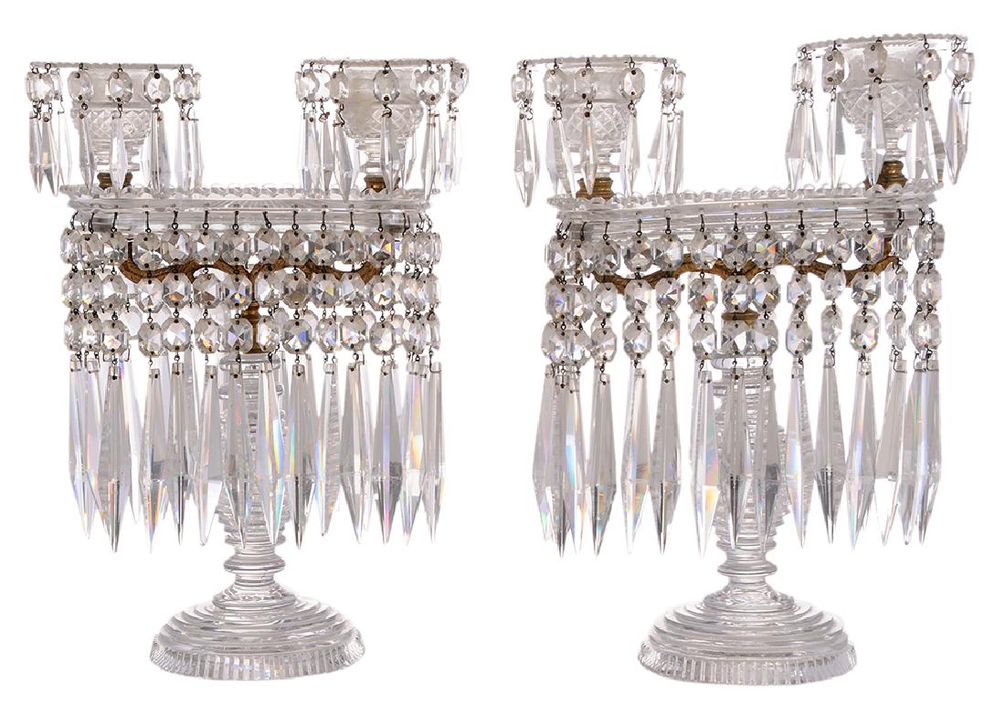 Pair Regency Twin Light Clear Cut Glass Lustres: British, 19th century, each raised on circular stepped domed bases with beehive ring standards issuing a pair of gilt bronze leafy S-scroll arms, joined by rectangular pans supporting a pair of facete